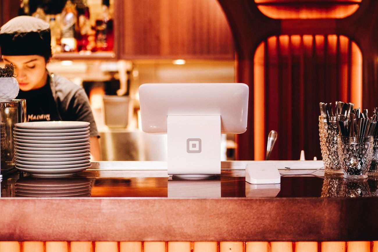 A customer paying at the counter of a small business that offers group health coverage to its staff